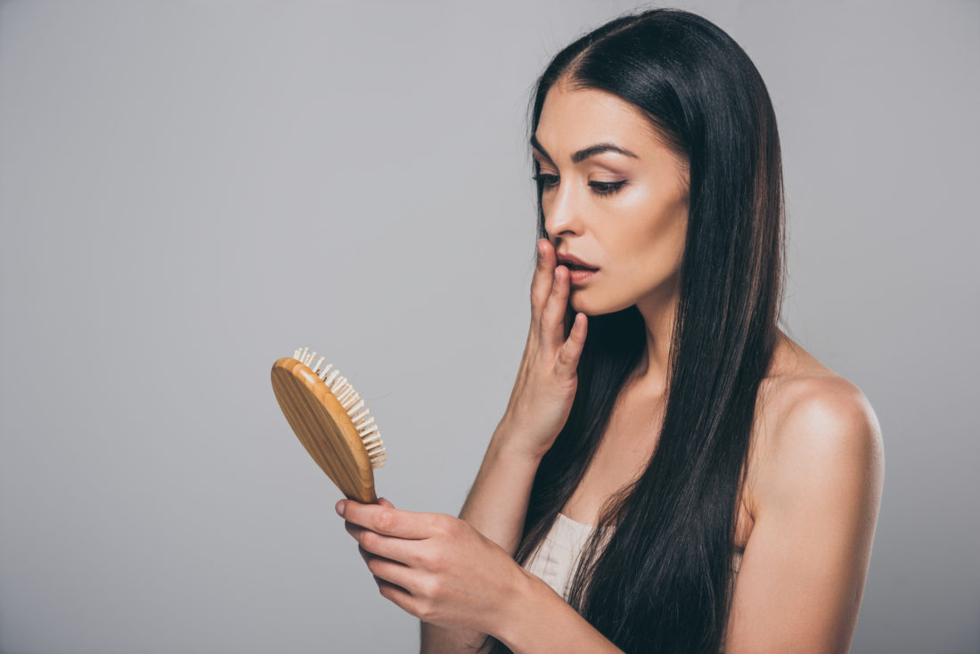 Hair Loss Doctor NYC - woman shocked looking at hair brush